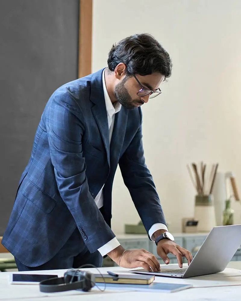A man standing up working on his laptop
